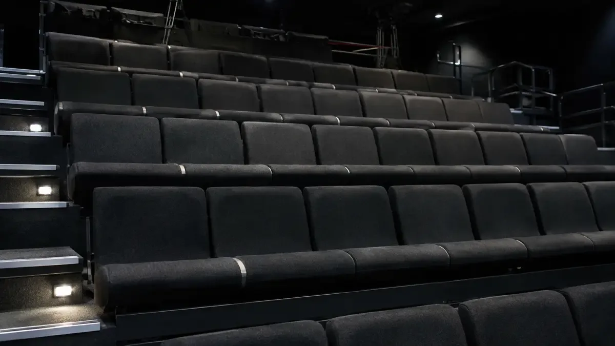 Gradas de publico vacias de un estudio de television con luces bajas