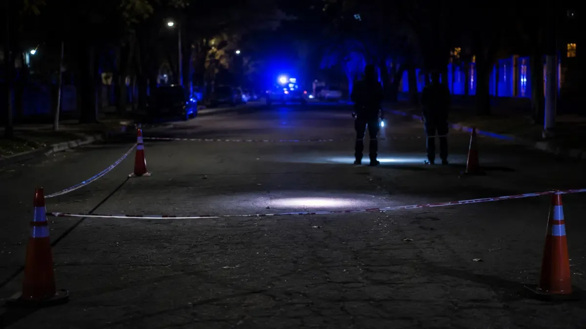 Haz de linterna iluminando el asfalto dentro de un perímetro con conos