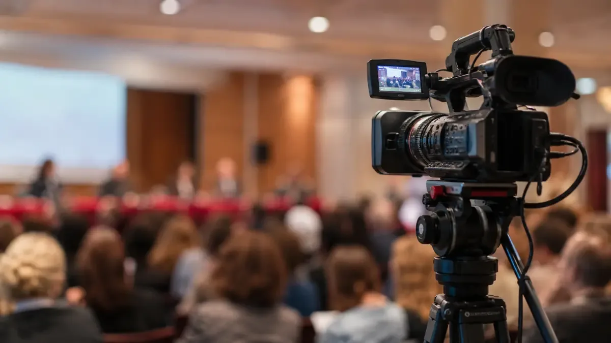 Camara de television en tripode con publico desenfocado al fondo
